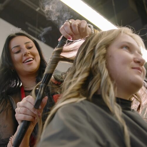 Hair stylist curling a client’s hair in a salon