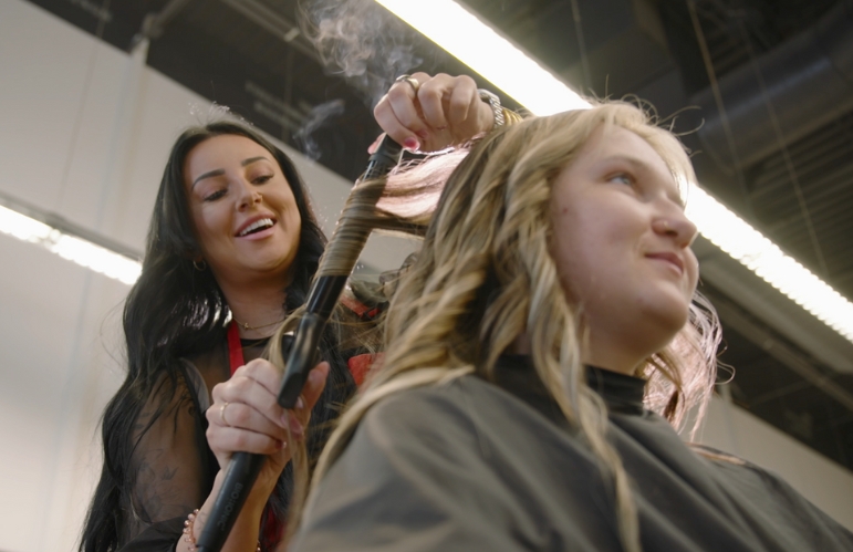 Hair stylist curling a client’s hair in a salon